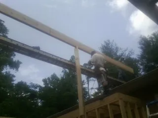 Carpenter setting a ridge beam over a new addition frame — Ice Dam Removal by Roofing Brothers in Alburnett