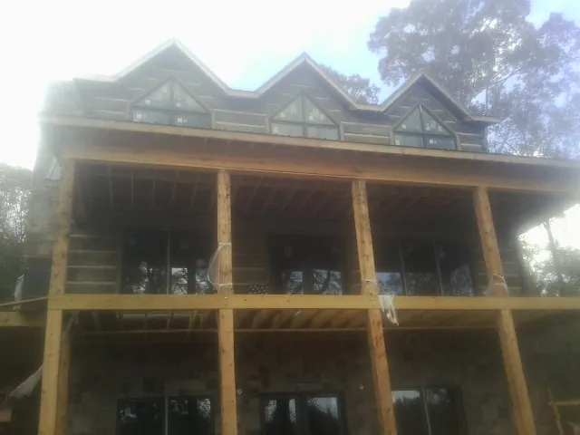 Dormers and porch framing on a large log home under construction — Roof Coating work by our crew in Alburnett