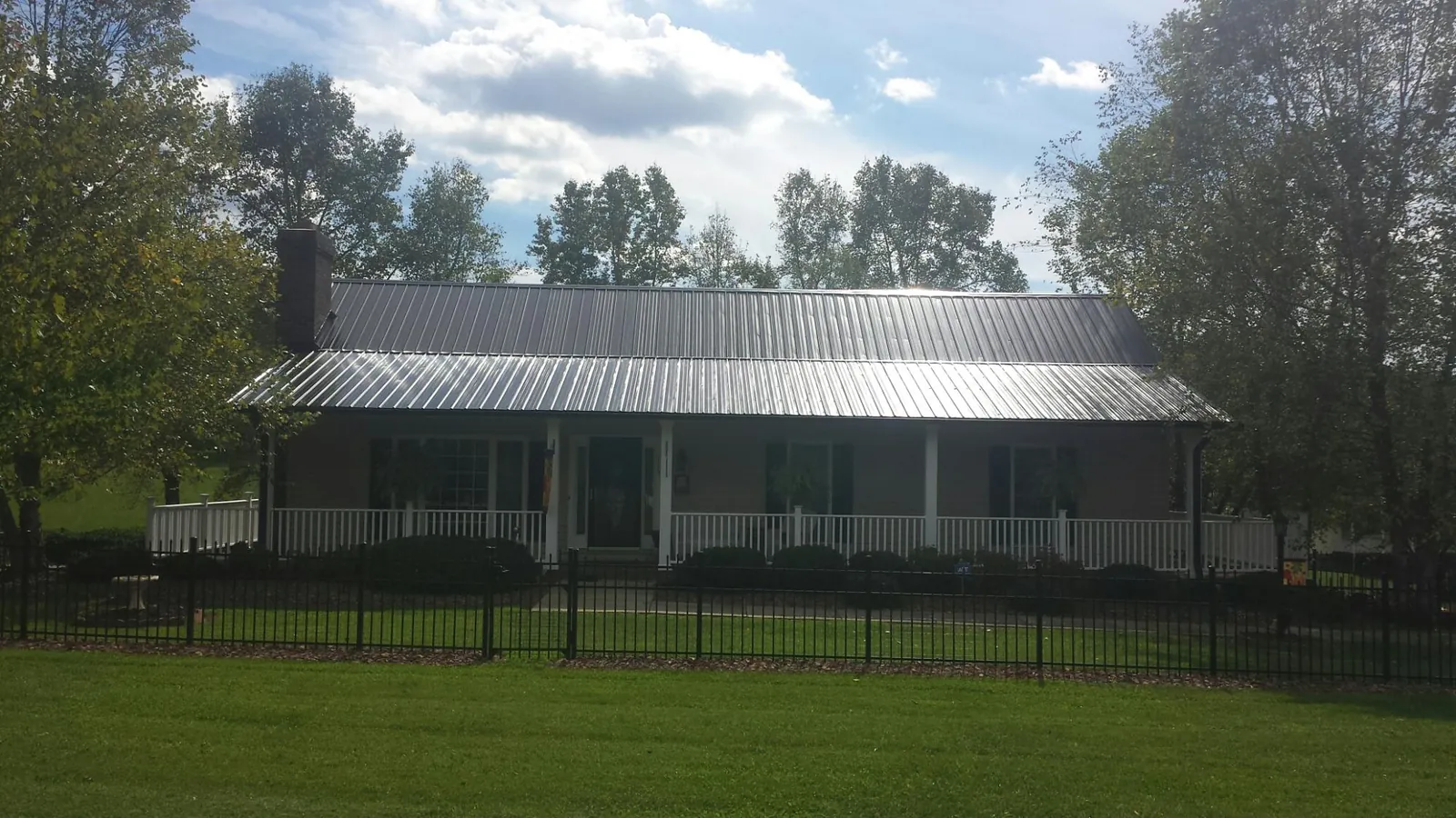 Gray metal roof on a brick ranch with a full width front porch — Gutter Guard Installation work by our crew in Alburnett