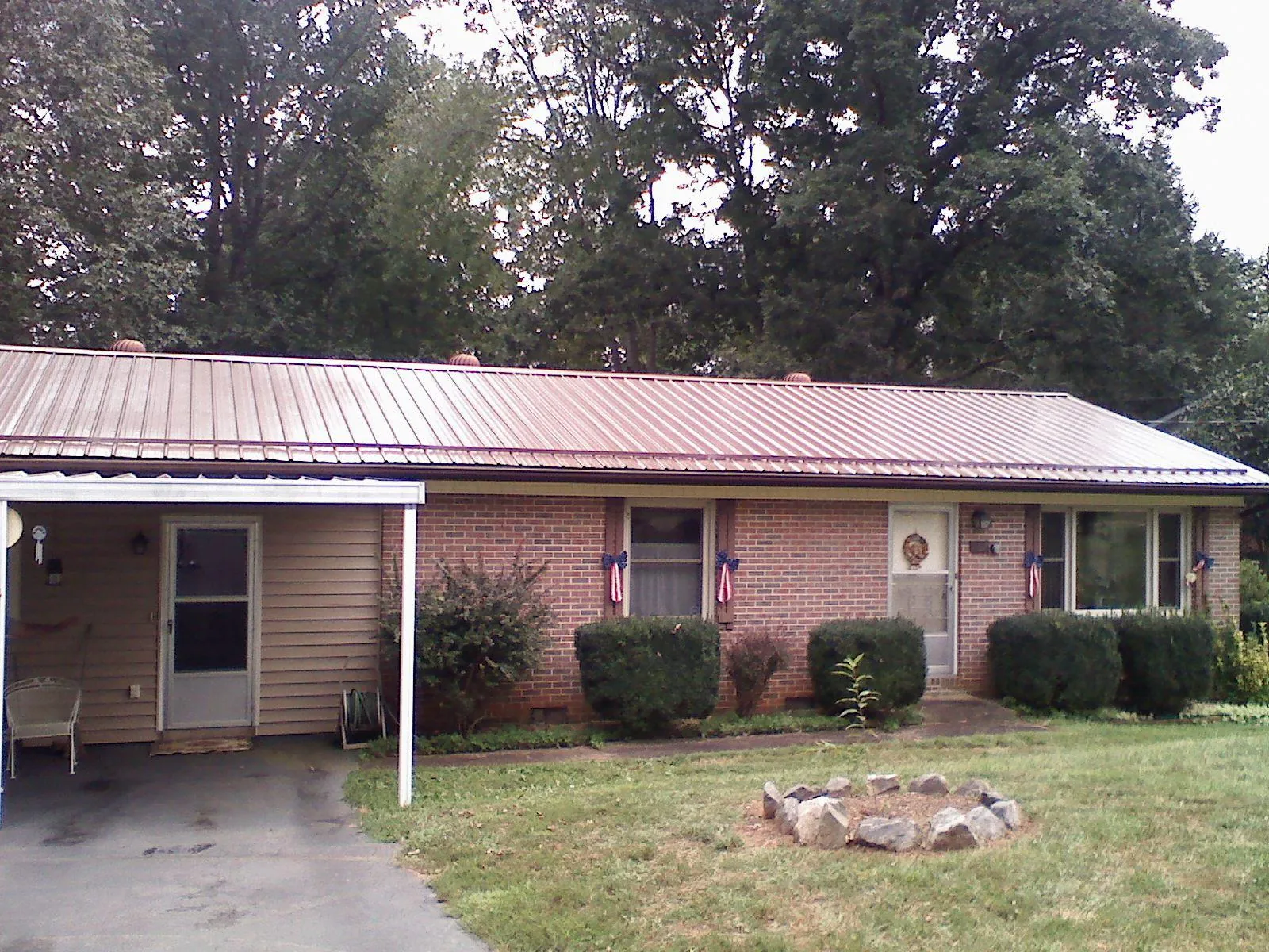 Bronze metal roof and carport on a brick ranch home — Roof Repair work by our crew in Alburnett