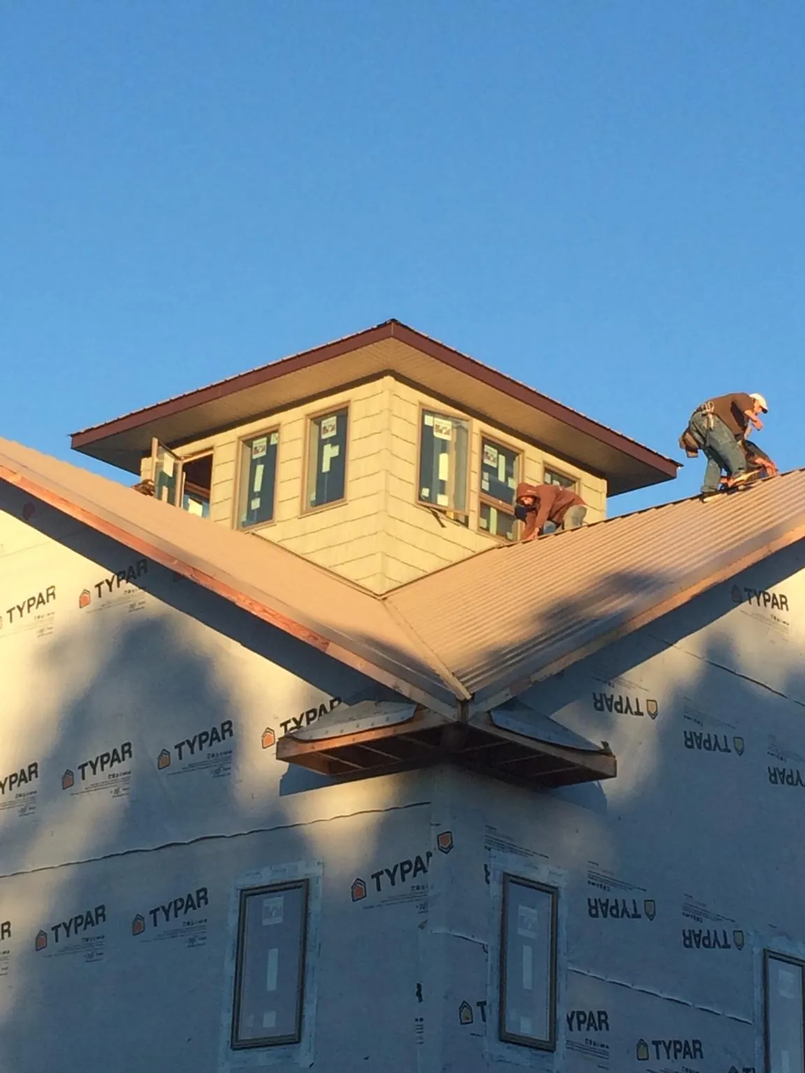 Roofers working around a rooftop cupola on a new metal roof at sunset — Roof Waterproofing in Alburnett by Roofing Brothers